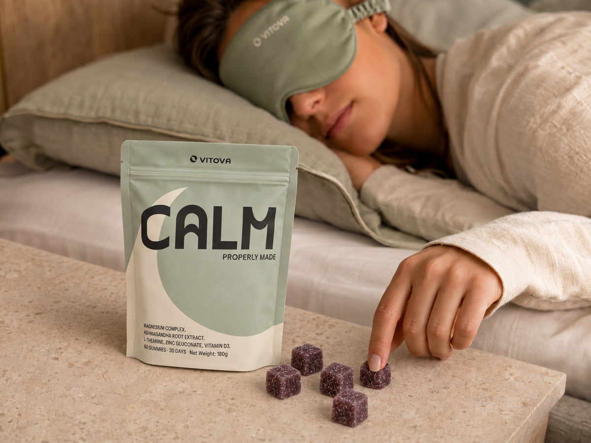 Sage Vitova Calm pouch and purple gummies on a bedside table with a woman resting behind them.