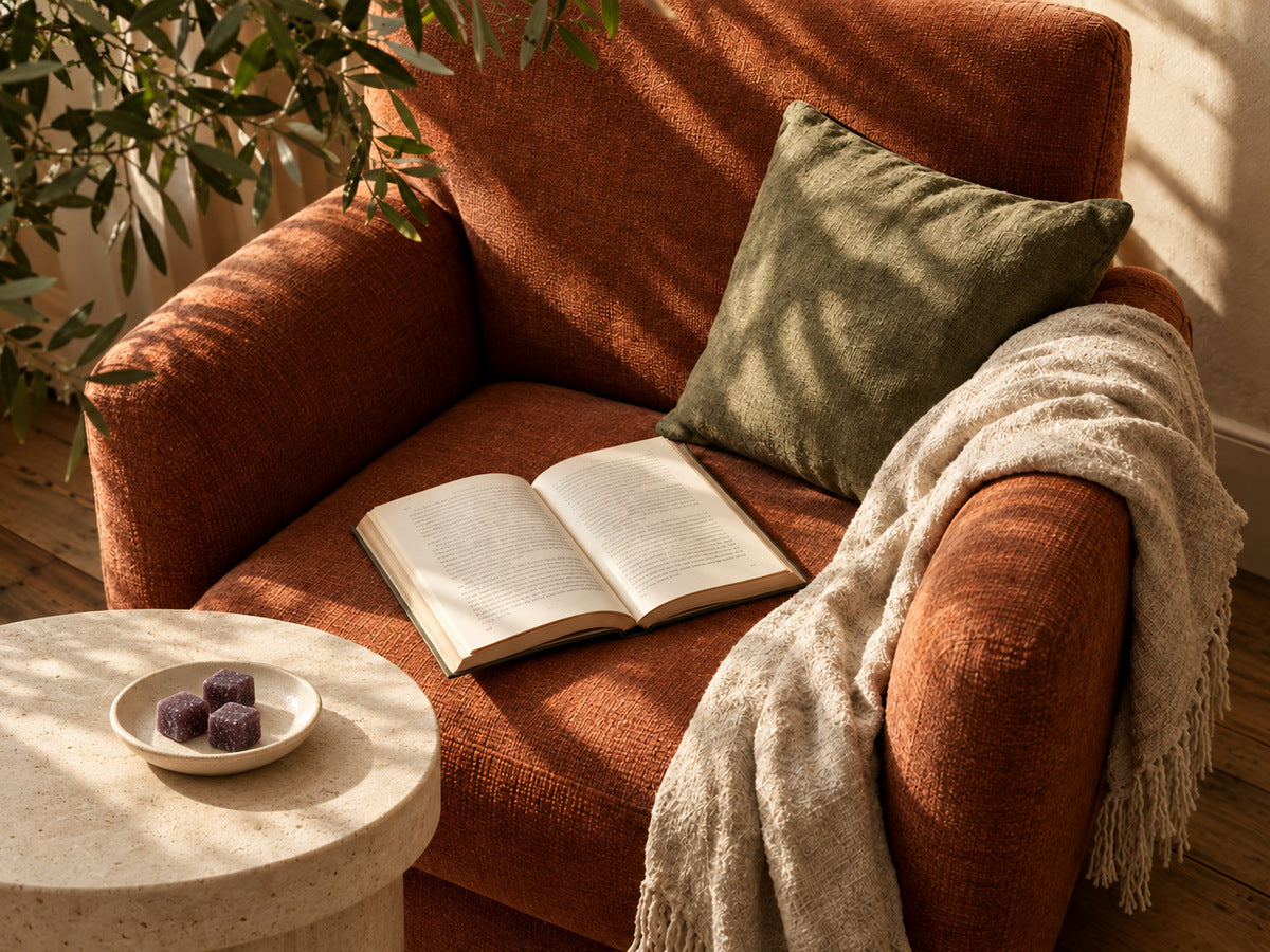 Purple gummies in a small ceramic dish beside a terracotta reading chair and open book.