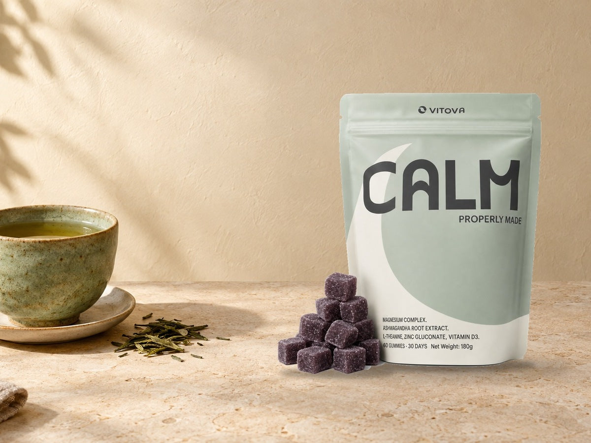 Vitova Calm pouch and purple gummies beside a ceramic cup of green tea.
